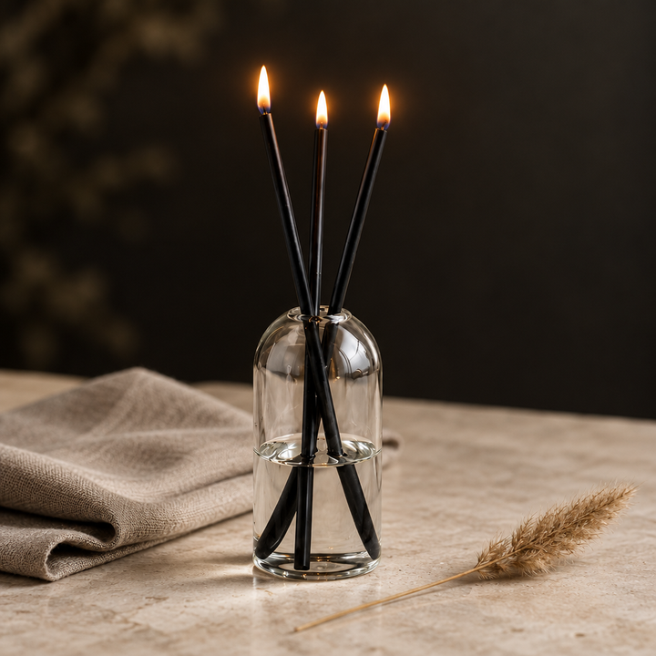 Glass oil candle set burning on a stone surface